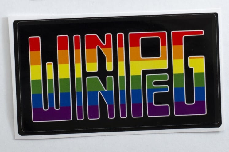 The text 'Winnipeg' filled with the rainbow pride flag colours on a black background and with a thin white border aroudn the text.