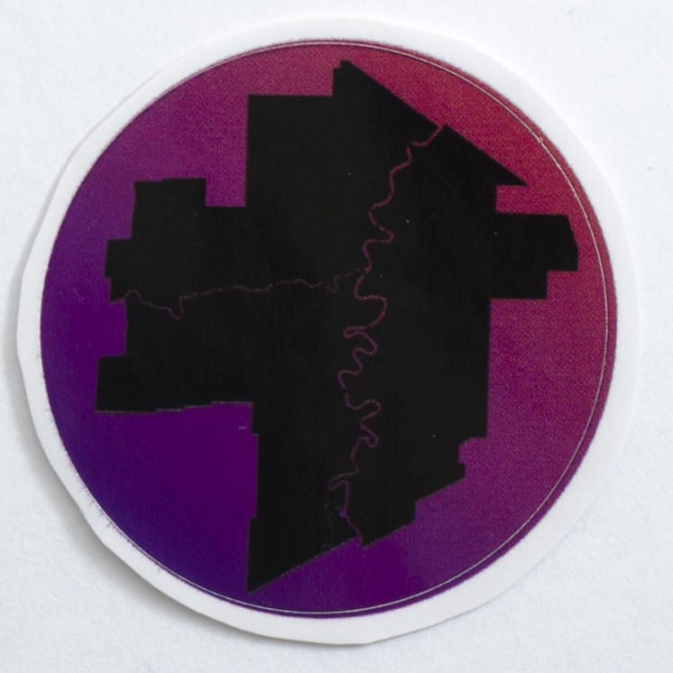 Circle design with purple/pink background and a black silhouette of the City of Winnipeg outline, hilighting Winnipeg's rivers